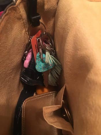 the hook on the side of a purse holding keychains