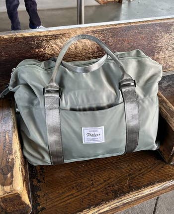 reviewer image of bag in a green-gray color sitting on a bench