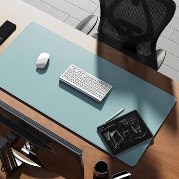 Keyboard, mouse, and notebook on waterproof desk pad