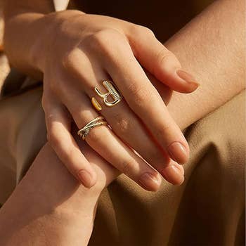 Close-up of hands featuring stylish gold rings, one with a bold