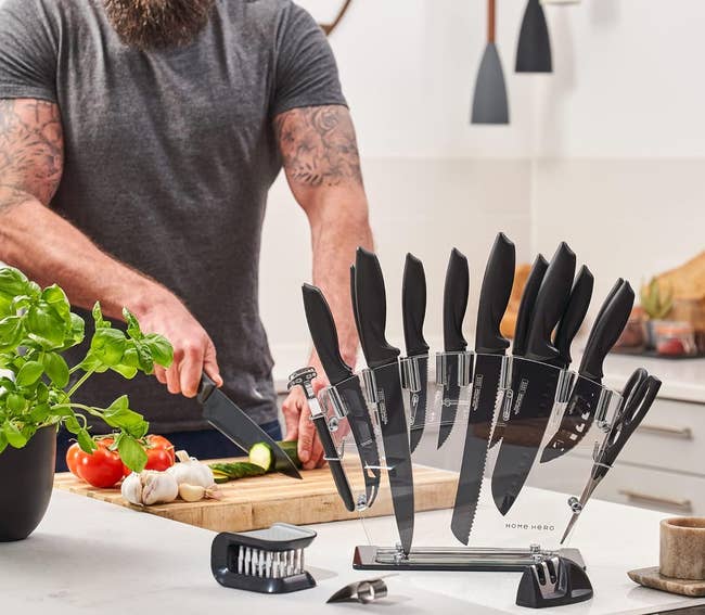 model cutting vegetables in the background with the knife set in the foreground on the clear stand showing all the tools