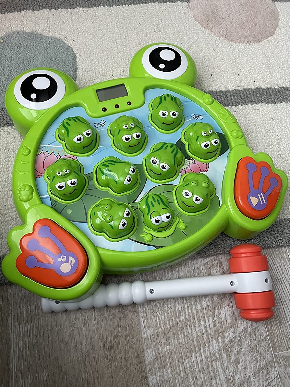 Reviewer image of green frog-shaped game with plastic hammer 