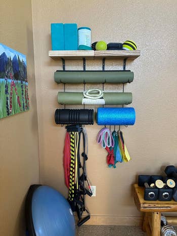 reviewer's workout station with yoga mat holder attached to wall with yoga mats and other exercise equipment