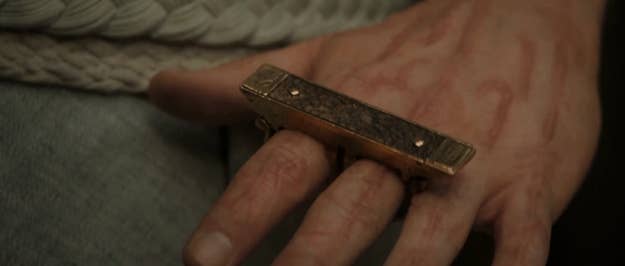 A hand holding an ornate, small, rectangular box with intricate detailing