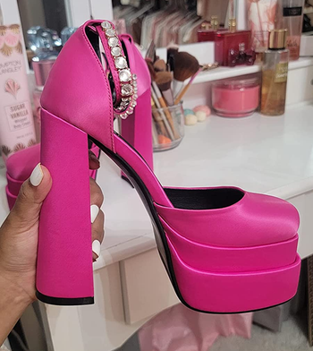reviewer holding the bright pink shoes