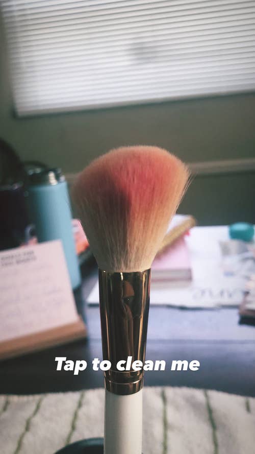 makeup brush with red blush on bristles