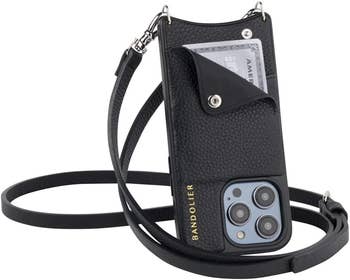 A black crossbody wallet-shaped bag with a phone inside of it, plus a front flap open to reveal a credit card 