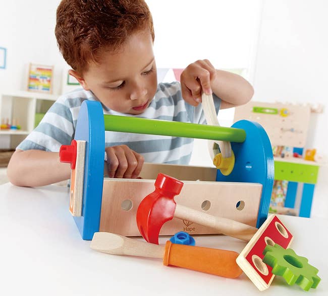 Child model playing with colorful wooden tool kit 