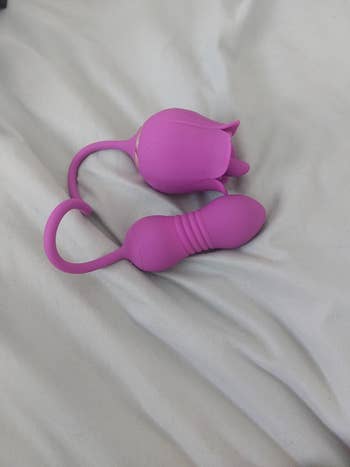 purple dual-stimulating rose vibrator on bedsheets