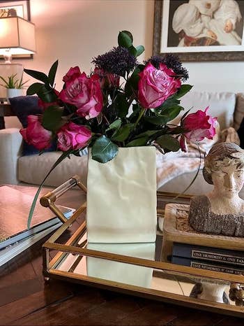 The vase on a table with pink roses in it