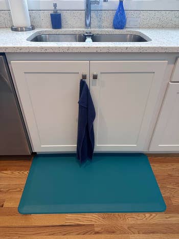 Kitchen descend  with a mat connected  the level  beneath   it and a towel hanging from furniture  handles