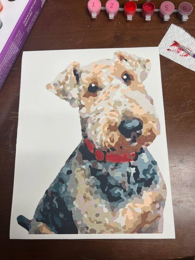 A reviewer's completed painting of an airedale with numbered paint pots in the background