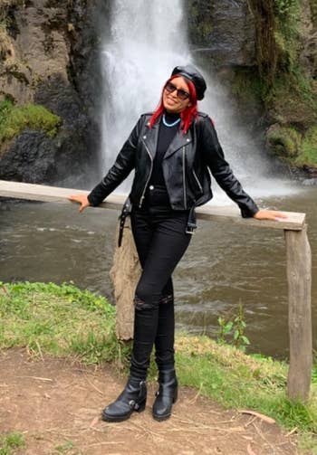 reviewer posing in front of a waterfall wearing a leather jacket