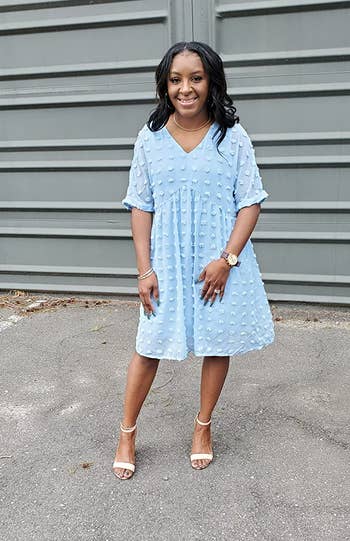 Reviewer is wearing a baby blue shift dress with textured dots throughout