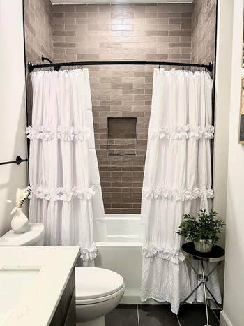 reviewer's white ruffled shower curtains in a bathroom 
