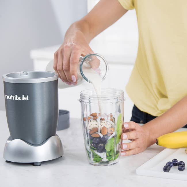 A blender with fruits, vegetables, and nuts in it