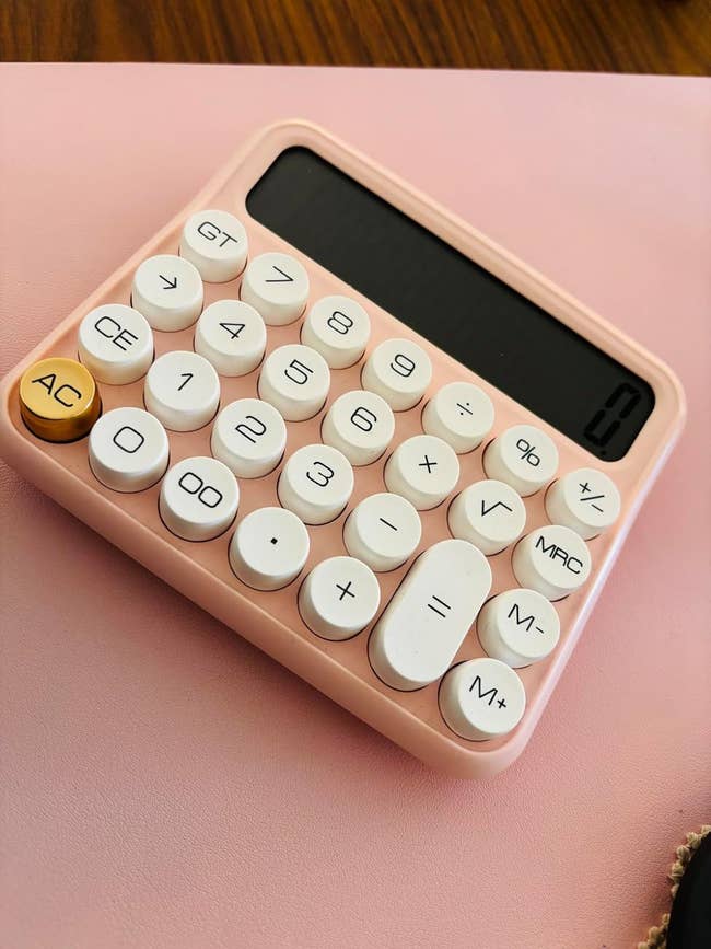 Compact calculator with circular buttons connected a desk