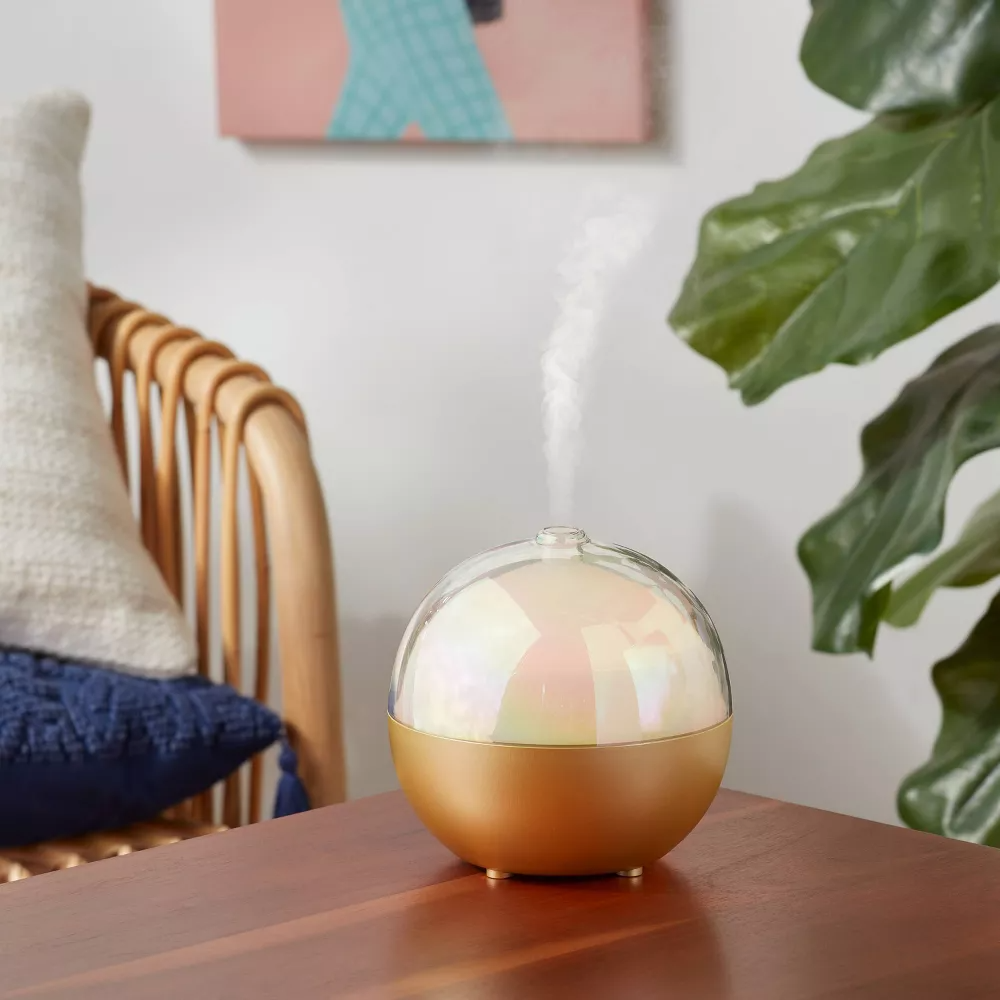 round diffuser with shiny inside, gold base, and a glass covering on top