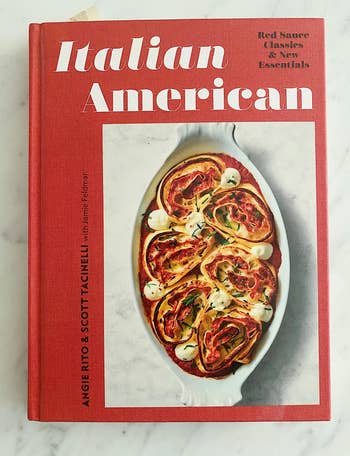the red Italian American cookbook featuring a dish of rolled lasagna on the cover