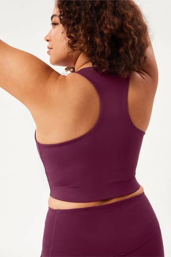 model in purple version with back turned to show the racerback strap 