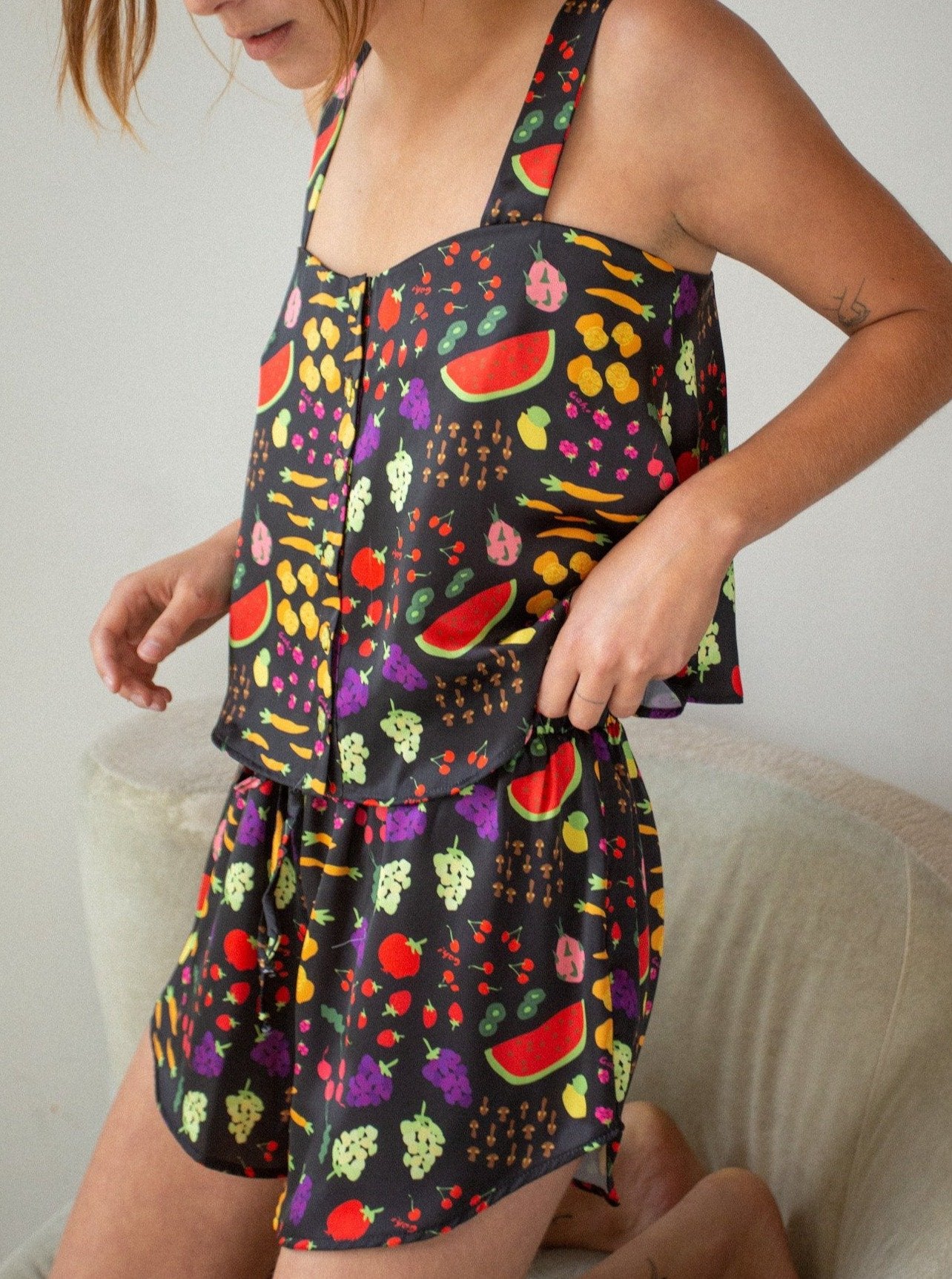 model wearing the black set with colorful fruit printed all over it