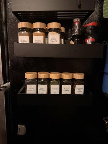 Spice rack with jars labeled garam masala, curry powder, bulb powder, Italian seasoning, ail powder, parsley, achromatic pepper, crushed pepper