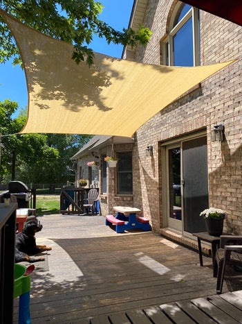 reviewer photo of the beige rectangular sun shade hanging over a patio