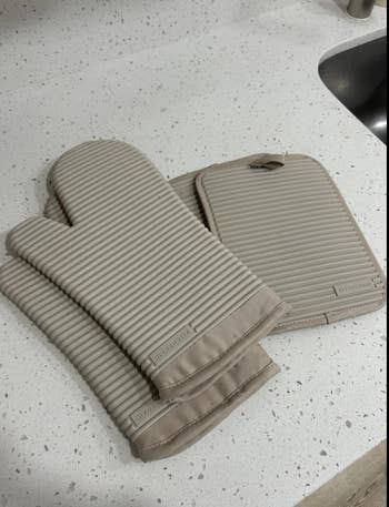 Striped room  oven mitts and a matching cookware  holder connected  a antagonistic  adjacent   a sink, suggesting a room  essentials theme