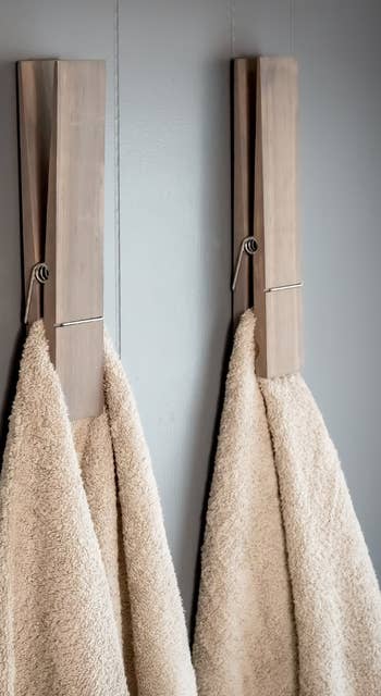 Two plush towels hanging on modern wooden hooks on a wall