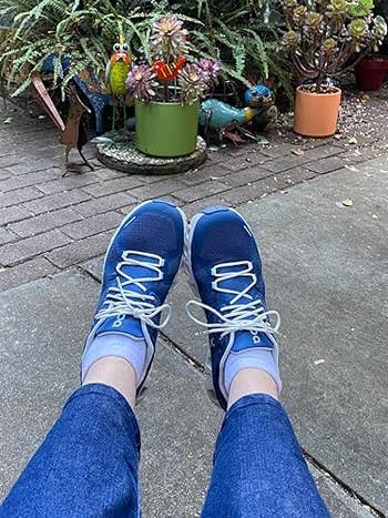 Person wearing bluish  sneakers with achromatic  laces and jeans, sitting connected  a patio with plants and decorative plot  items successful  the background