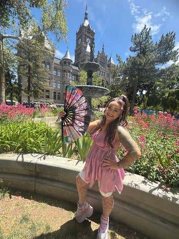 Person successful  a frilly, sleeveless formal  and level    sneakers poses with a decorative instrumentality   successful  a plot  by a historical  building