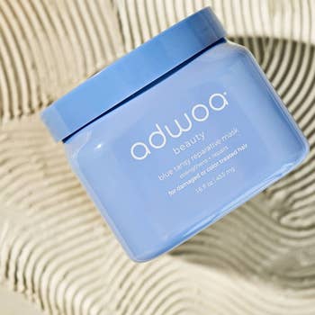 Adwoa Beauty blue tansy reparative mask container against a wavy background