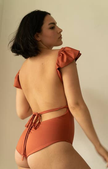 the back view of the model wearing the same swimsuit with an open back and tie in the back 