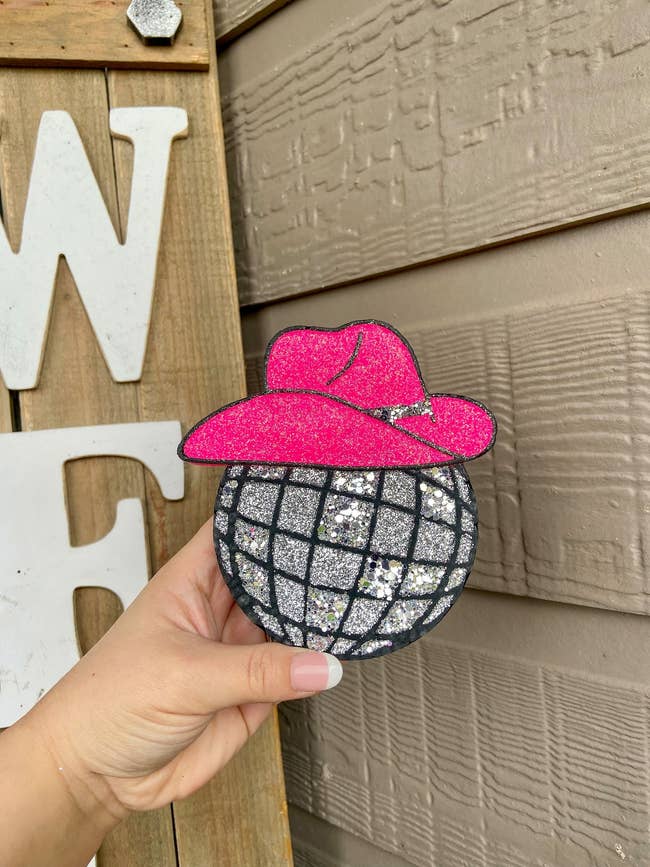 a car air freshener in the shape of a glittery disco ball with a pink cowboy hat on it