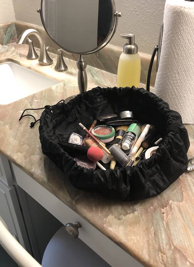 Reviewer photo of the lay n go bag on their counter with various make up products inside