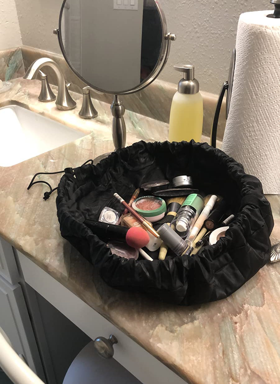 Reviewer photo of the lay n go bag on their counter with various make up products inside