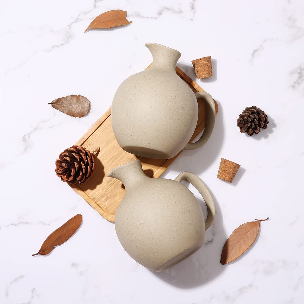 two squat ceramic bottles with cork lids. includes a tray and decorative leaves and pinecones surround product.