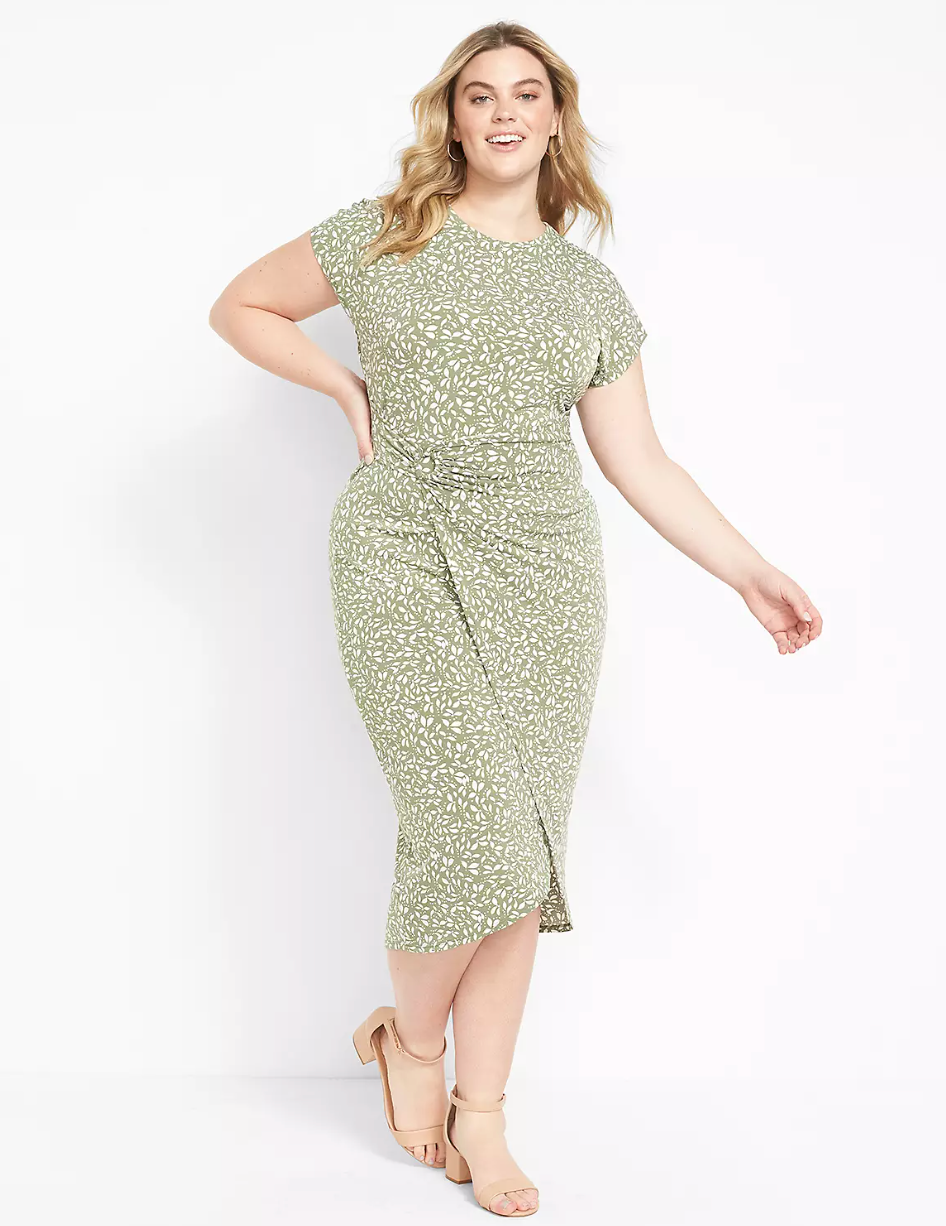 Model is wearing a pale green body con wrap dress with a white leaf pattern throughout and nude heels