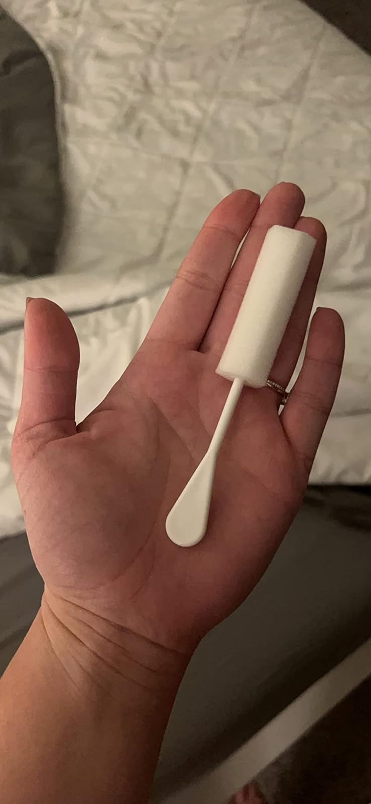 Hand holding a white foam and plastic sponge stick