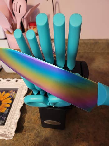A knife block with colorful kitchen knives, including one with a rainbow blade. Ideal for modern kitchen decor