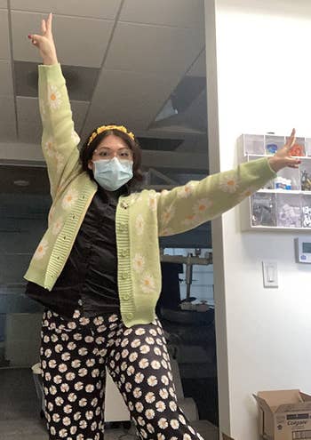 another reviewer in a pastel green cardigan covered in daisies