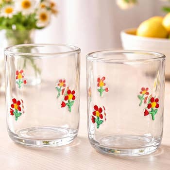 Two solid  tumblers decorated with tiny  floral designs lasting  connected  a airy  woody  surface