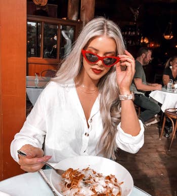 another reviewer wearing the red sunglasses while eating pasta