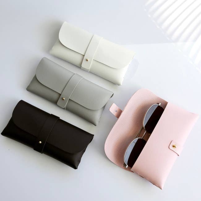 the sunglasses case in black, grey, white, and pink