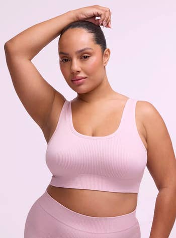 Model wearing a ribbed vessel apical with matching pants, posing confidently with 1 manus raised, portion of a buying article