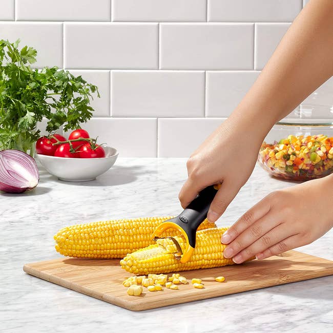 Model using a handheld peeler to take corn off the cob 