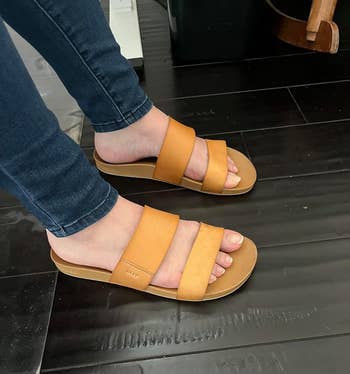 reviewer wearing tan slide sandals with wide straps, suitable for a casual shopping look