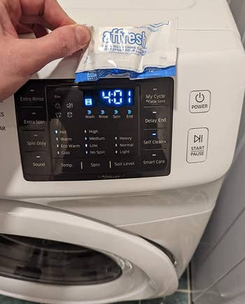 reviewer holding a cleaning tablet in front of a washing machine
