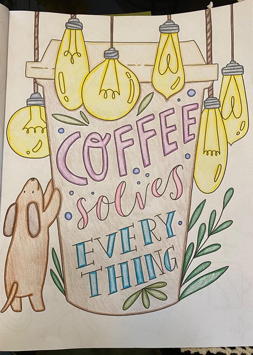 A reviewer's colored-in coloring book page featuring a dog leaning against a coffee cup that reads