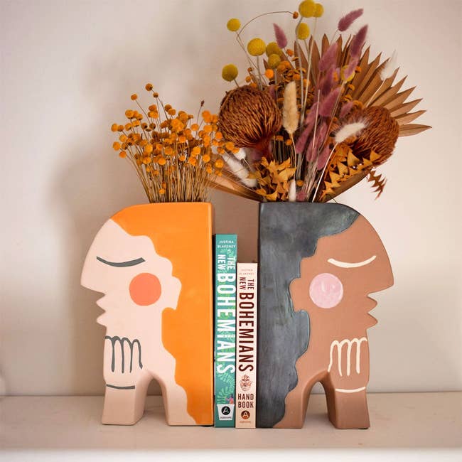 two bookends holding a dry floral arrangment and books in between